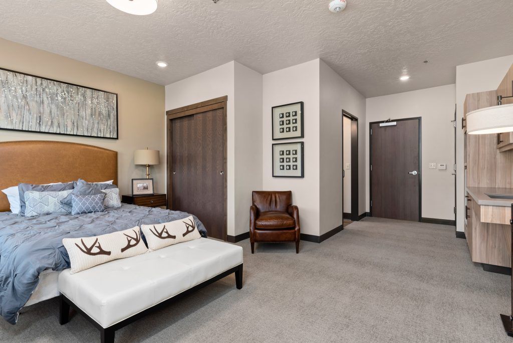 A modern bedroom with stylish furnishings, including a bed, leather chair, and decorative artwork.