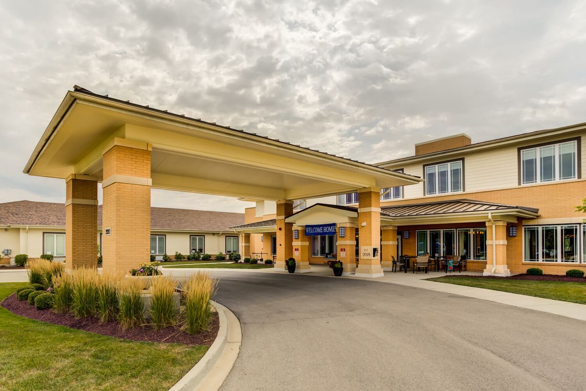 A modern building with an inviting entrance and a driveway under a cloudy sky.