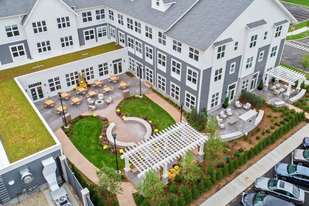 Aerial view of a residential complex with a landscaped courtyard featuring outdoor seating and garden areas.