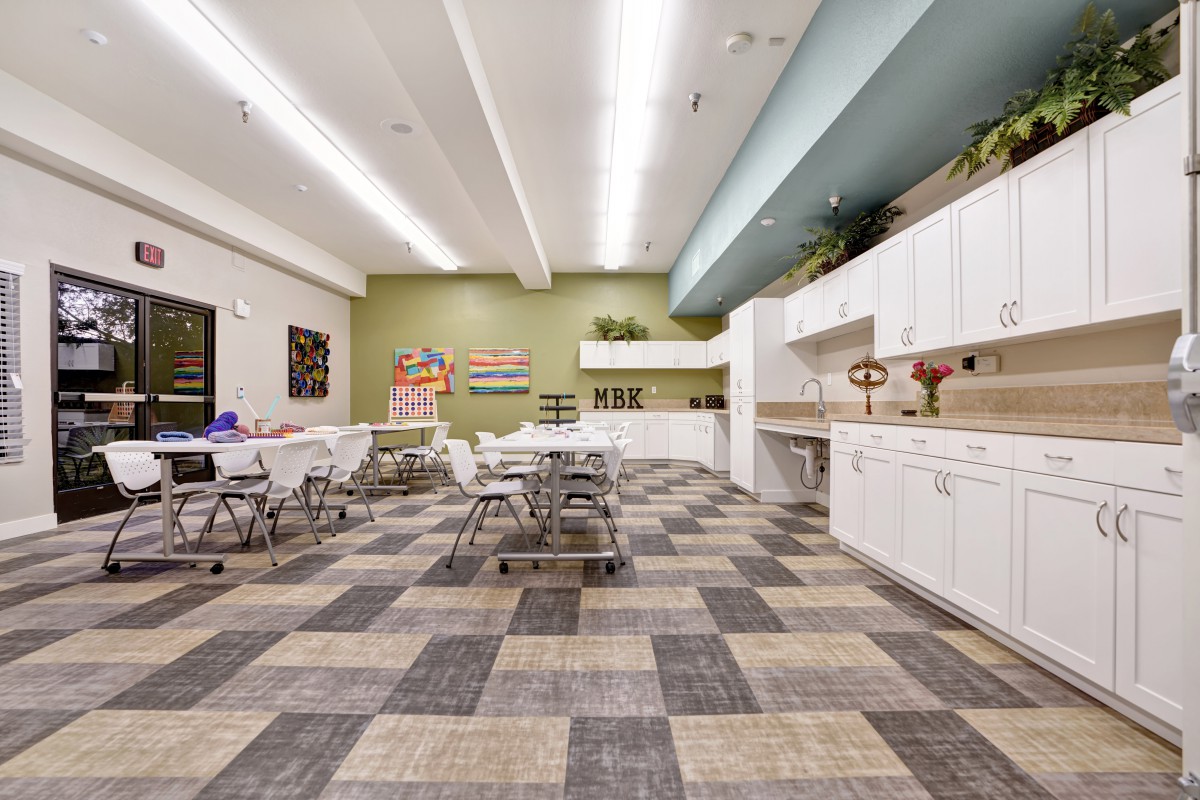 Modern kitchen and dining area with white cabinets and tiled flooring.