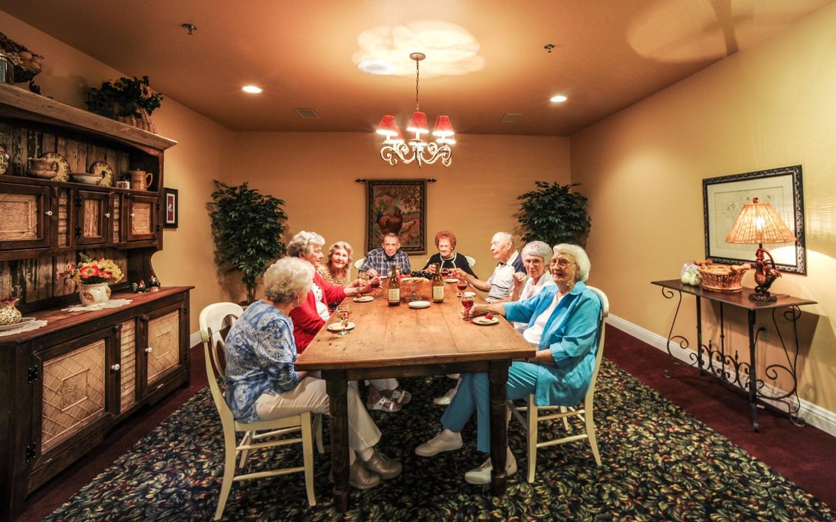 A group of elderly people enjoying a meal together around a dining table.