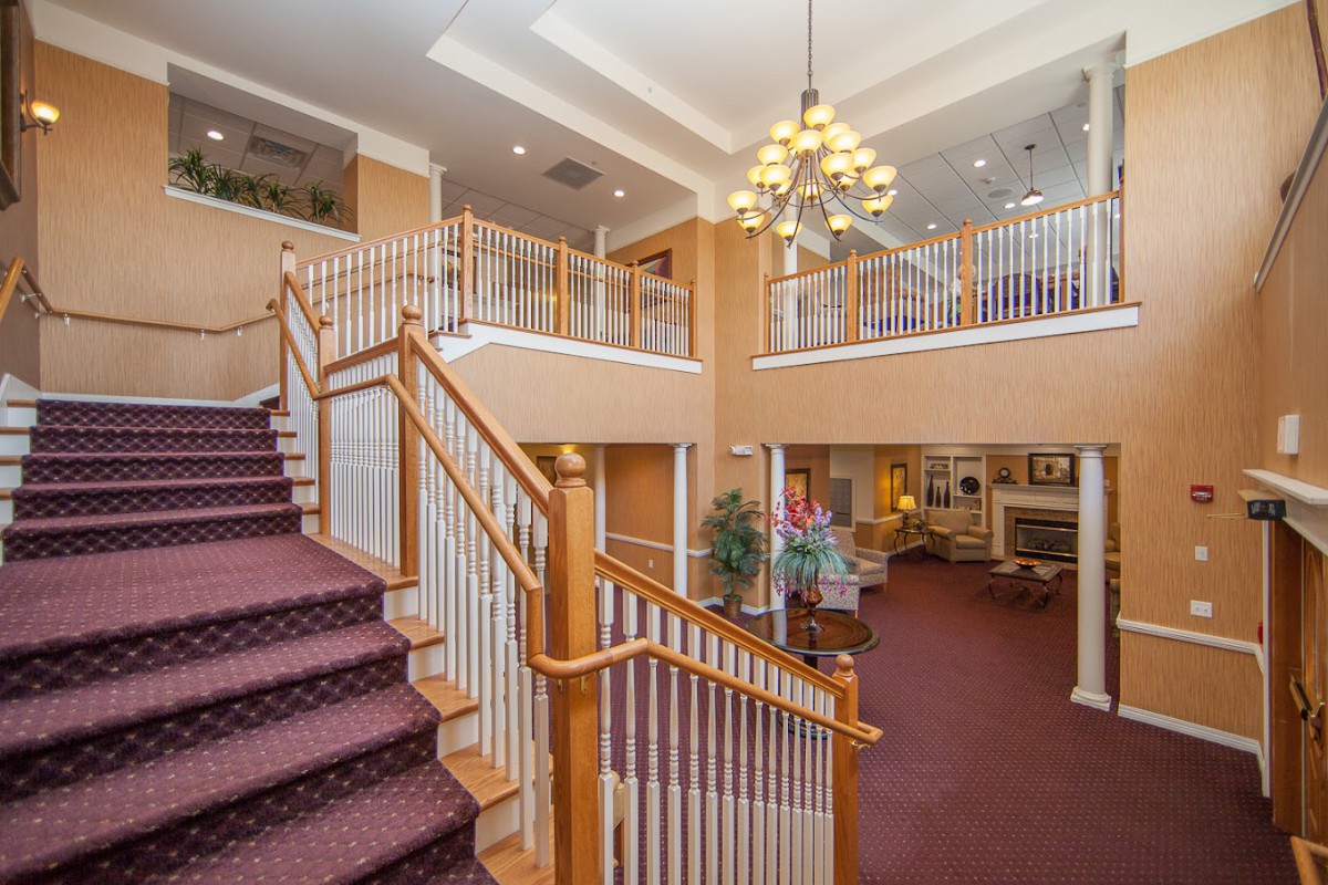 A spacious interior lobby with a grand staircase, ornate chandelier, and comfortable seating.