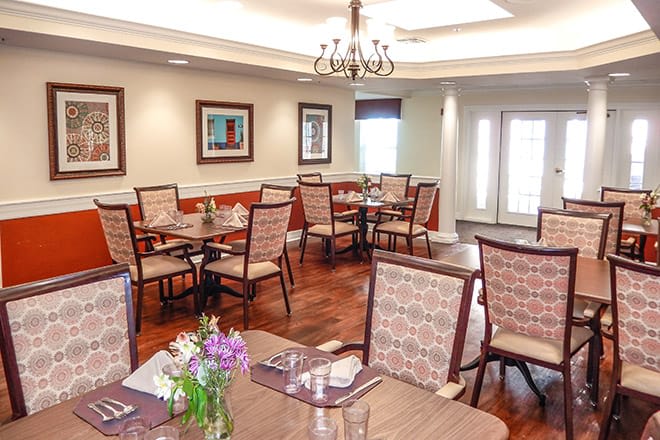 A well-decorated dining room with neatly arranged tables and chairs under a chandelier.