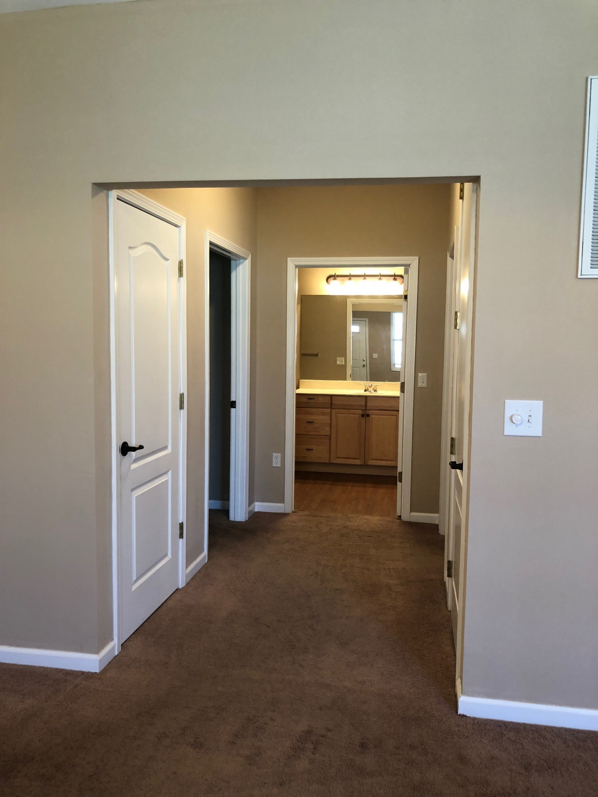 A view of a home's hallway leading to a bathroom with warm lighting.