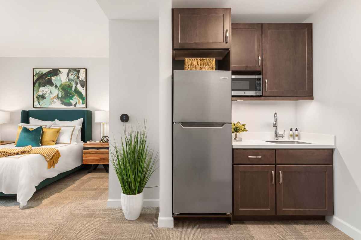 A modern apartment interior with a compact kitchen and adjacent bedroom.