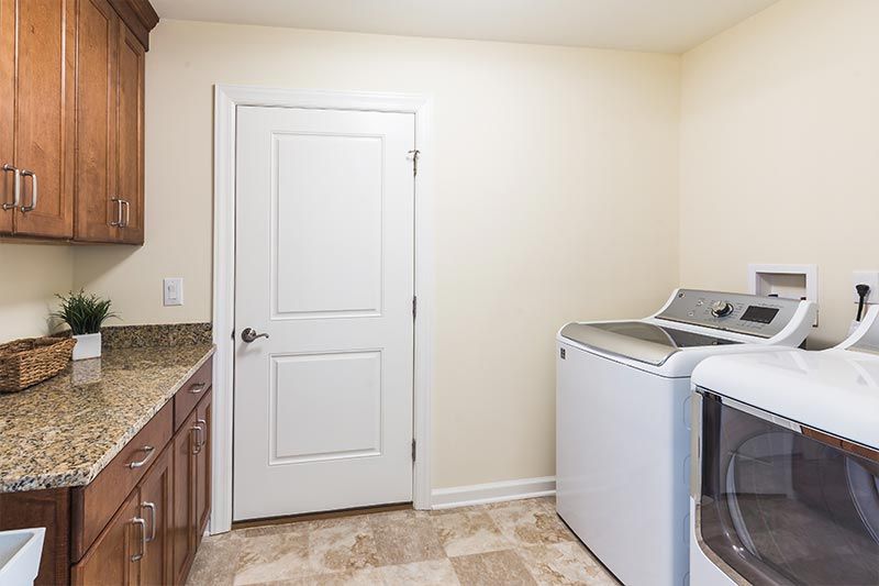 A laundry room with a washer and dryer next to a countertop and a door.