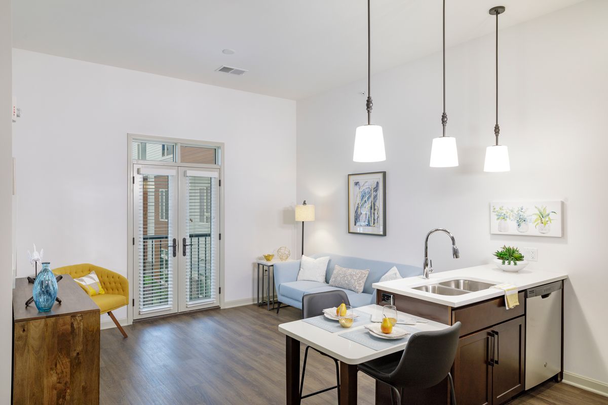 A modern open-concept living room and kitchen area featuring stylish furnishings and ambient lighting.