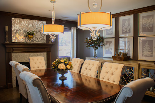A beautifully designed dining room featuring elegant chandeliers, a wooden table, and tasteful floral arrangements.