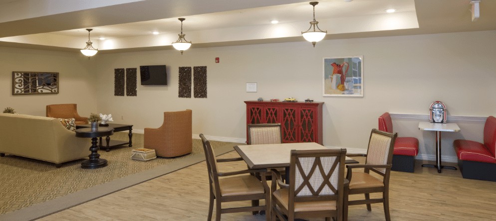 A cozy living and dining area with wooden furniture, a television on the wall, and artwork adding a decorative touch.