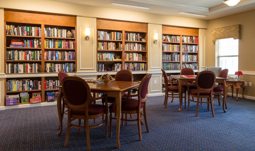 A quiet library reading area with bookshelves, tables, and chairs.