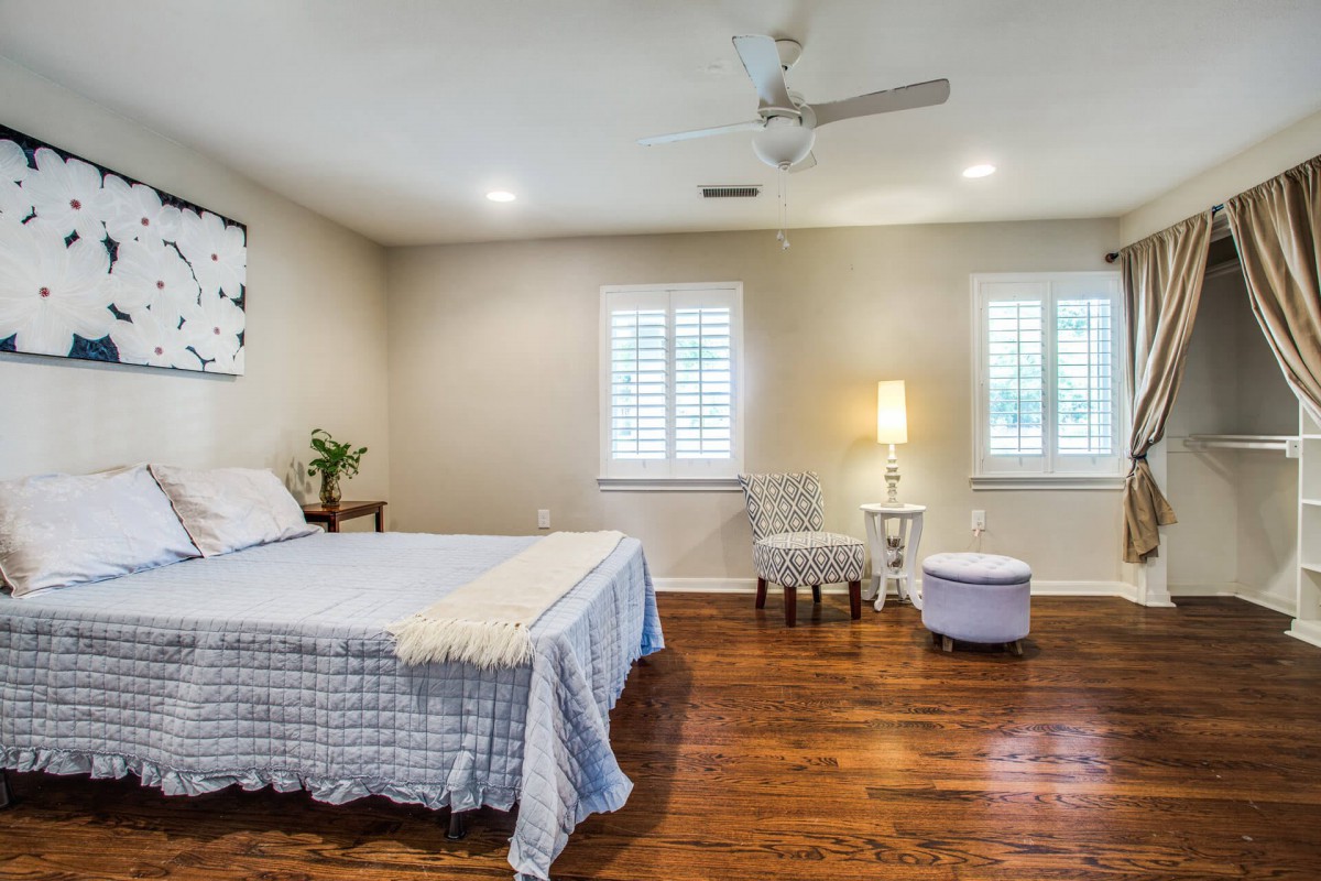 A cozy bedroom with hardwood floors, featuring a comfortable bed and a reading nook by the window.