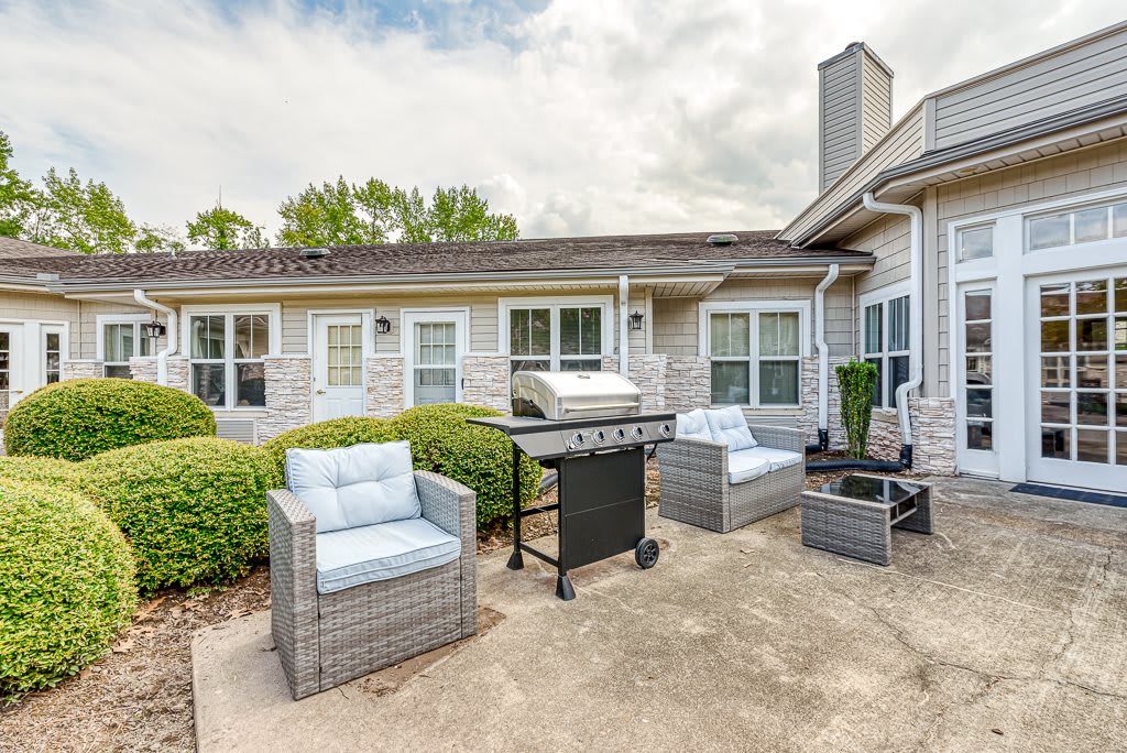A cozy patio setup with outdoor furniture and a grill in a backyard.