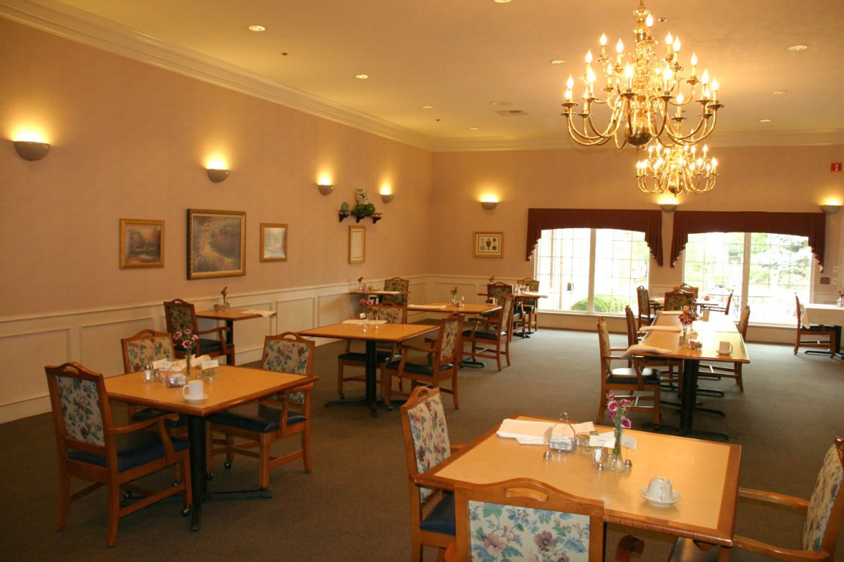 A cozy dining room with elegant chandeliers and neatly arranged tables and chairs.