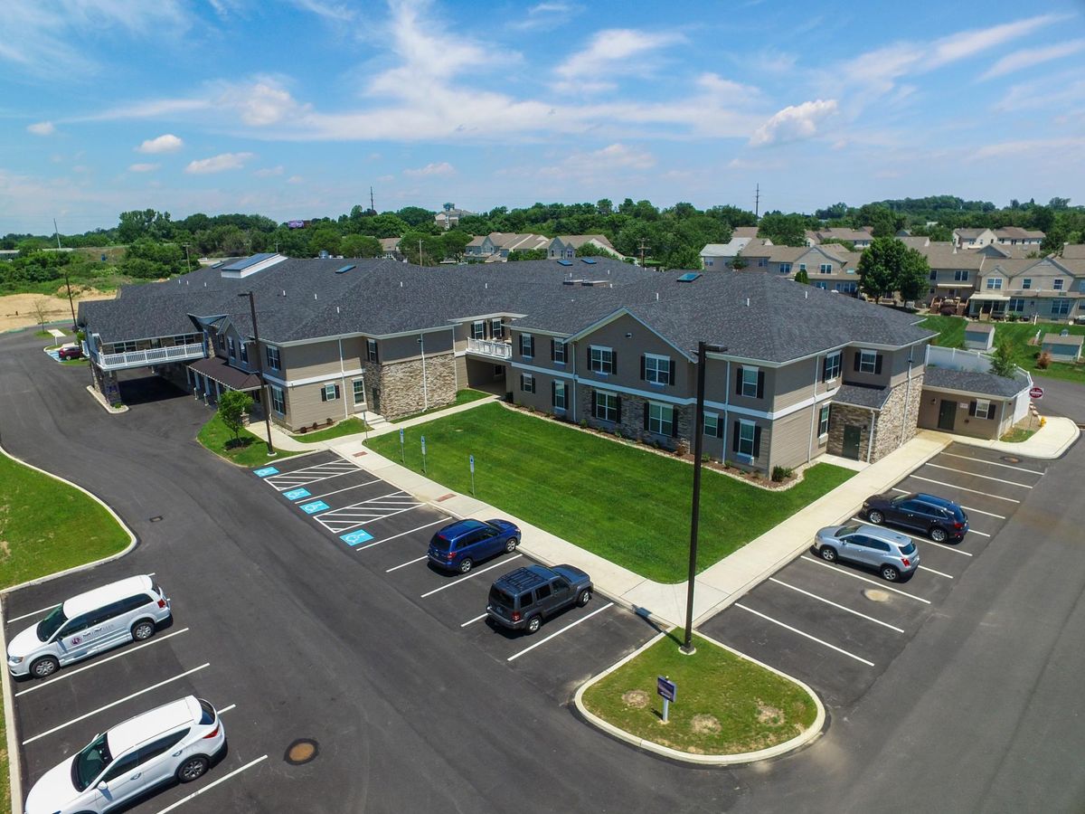 Aerial view of a modern building with an adjacent parking lot on a sunny day.