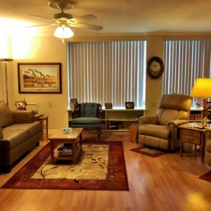 A cozy living room with a sofa, recliner, coffee table, and warm lighting.