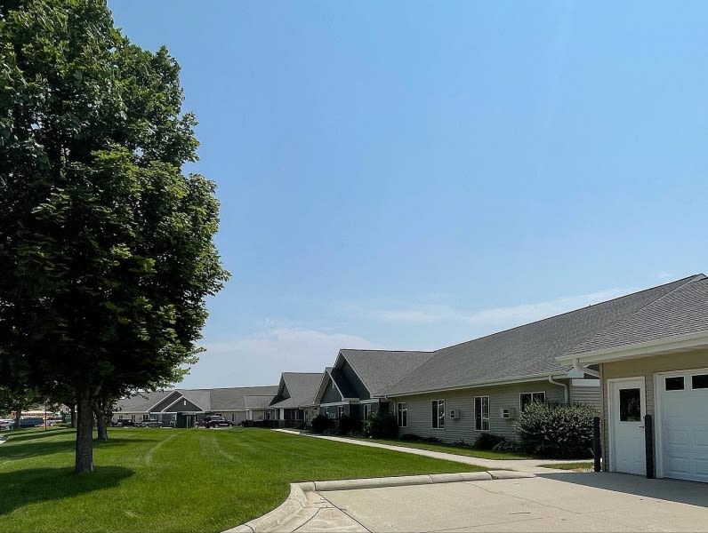 A peaceful suburban neighborhood with rows of houses, a well-maintained lawn, and a clear blue sky.