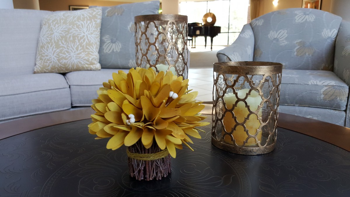 A stylish interior setup featuring a yellow flower arrangement and decorative candle holders on a table.