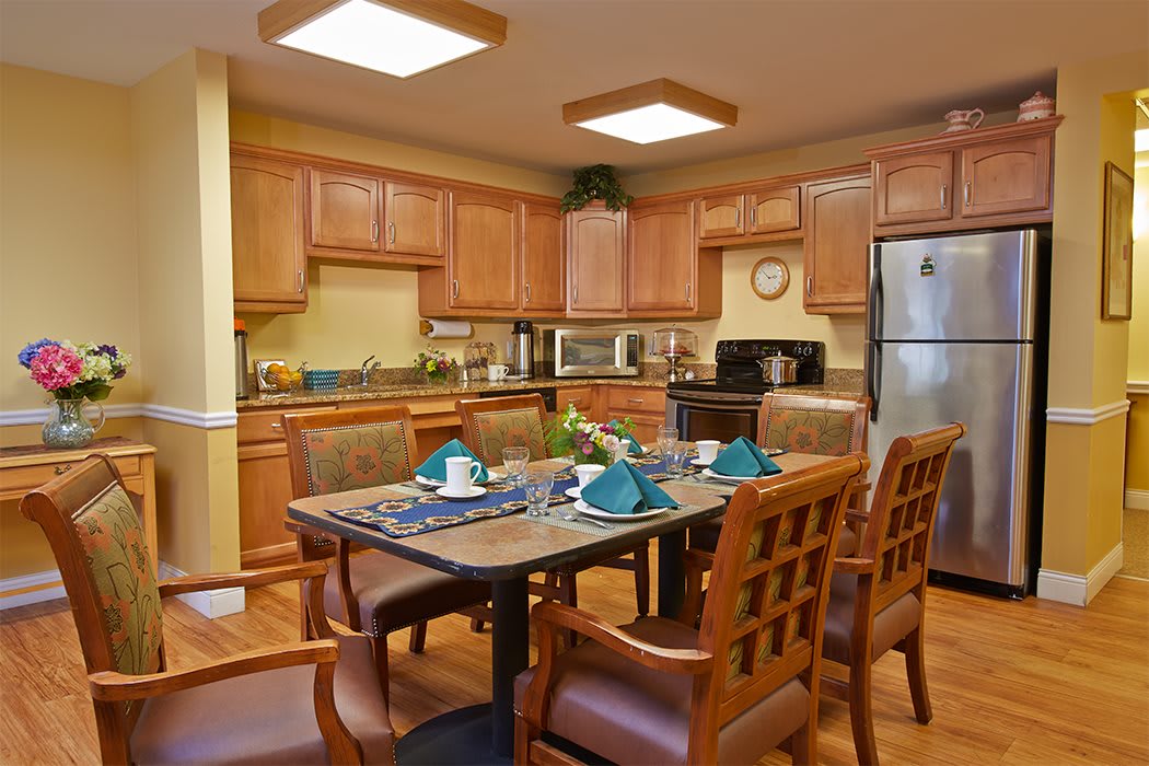 A cozy kitchen and dining area with wood cabinets and a neatly set table.