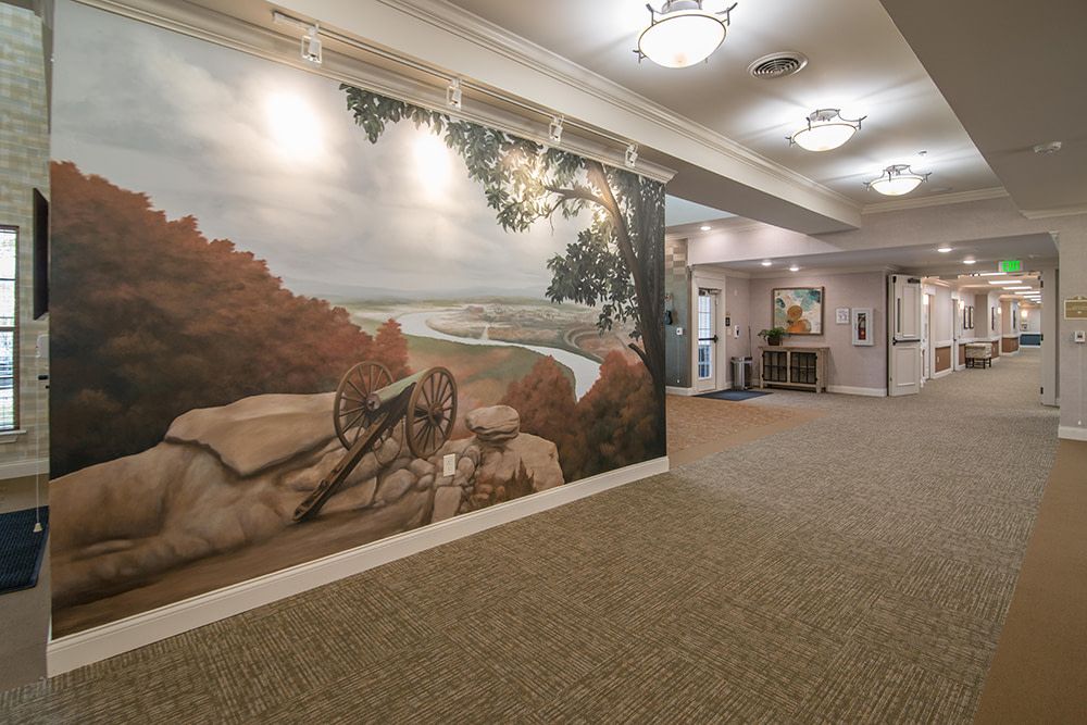 A hallway featuring a large mural depicting a scenic landscape with overhead lighting.