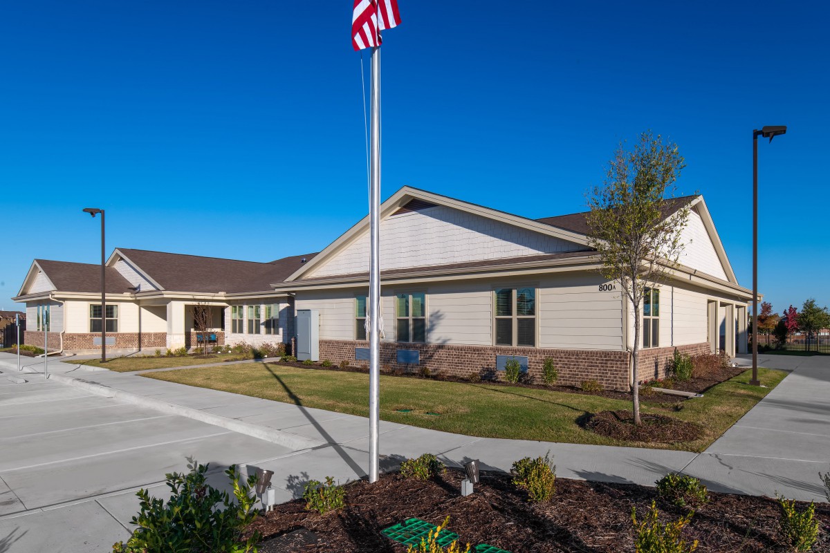 A single-story building with an American flag in front on a clear day.