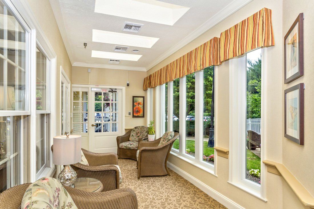 A bright and inviting sunroom with large windows, wicker chairs, and warm lighting.
