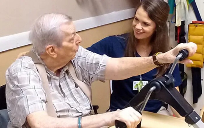 A caregiver interacting with an elderly person in a healthcare setting.