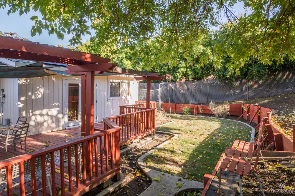 A cozy backyard with a wooden deck and lush greenery.