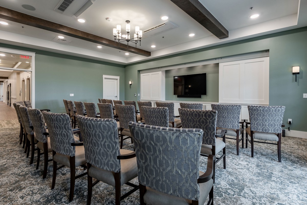 A well-arranged conference room with patterned chairs and a large screen at the front.