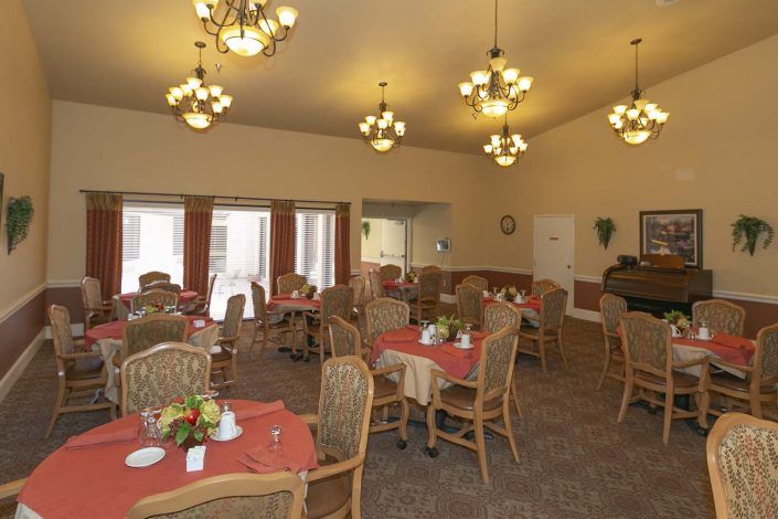 A warmly lit dining area with multiple tables and chairs set up for a meal.