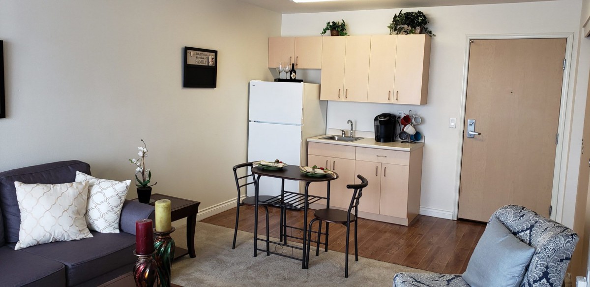 A compact kitchen and dining area with a refrigerator, small table, and chairs.