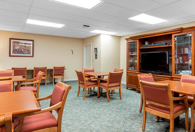 A spacious dining and living area with tables, chairs, and a television.