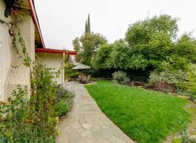 A serene backyard garden with a lush lawn and stone pathway.