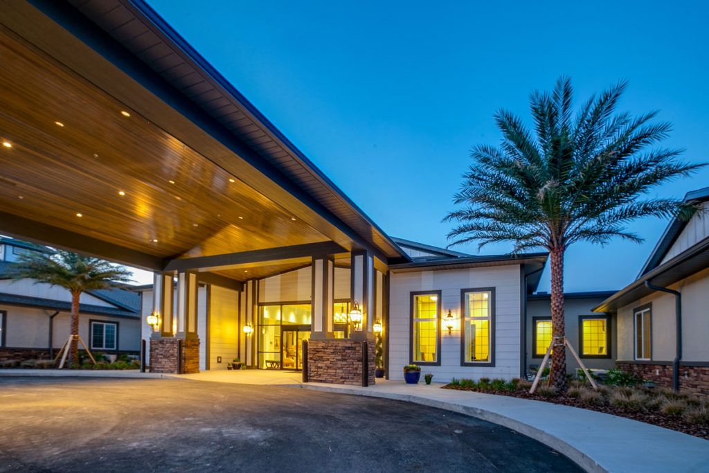 A modern building entrance illuminated at night with a palm tree nearby.