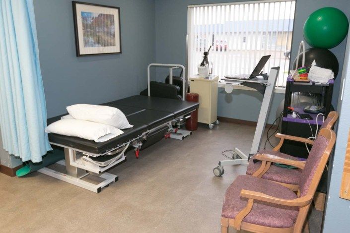 A medical examination room with a therapy table and various equipment.