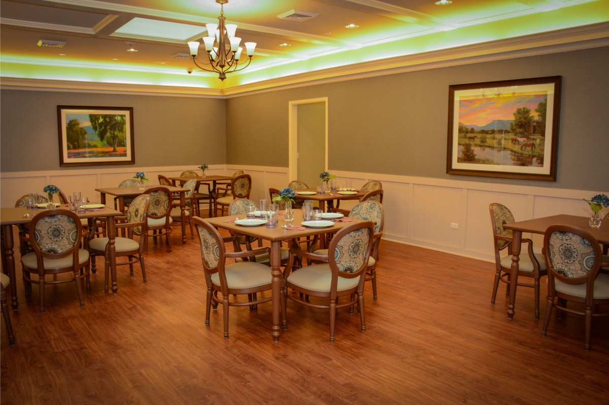 A cozy dining room setting with tables and chairs, elegant decor, and warm lighting.
