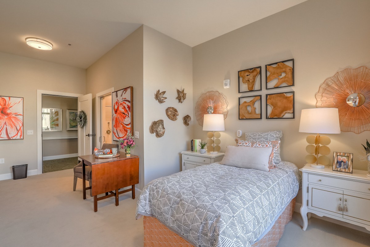 A cozy bedroom with a single bed, decorated with wall art and warm lighting.