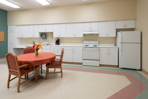 A spacious and bright kitchen with a dining area featuring a round table, chairs, and modern appliances.