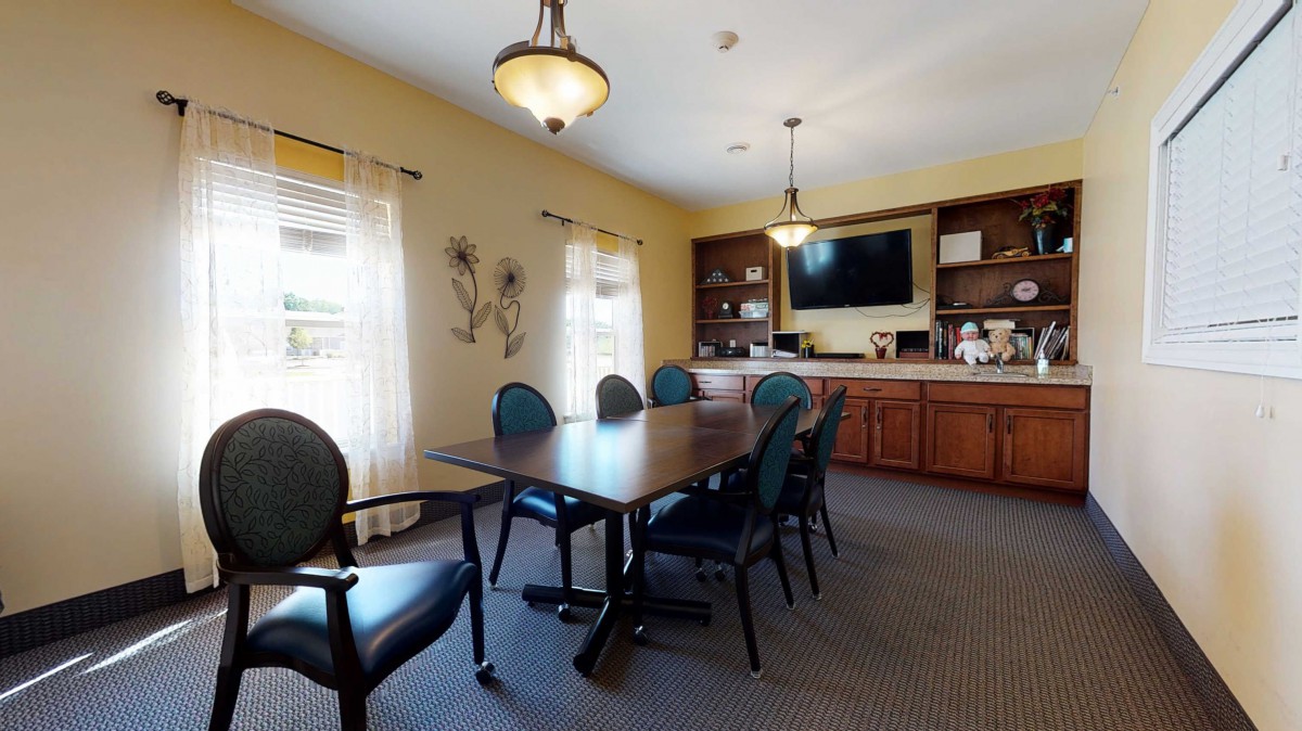 A well-lit conference room with a meeting table, chairs, and a TV on the wall.