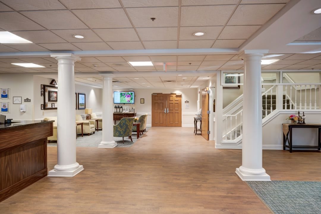 A spacious lobby with columns, seating area, and stairs.