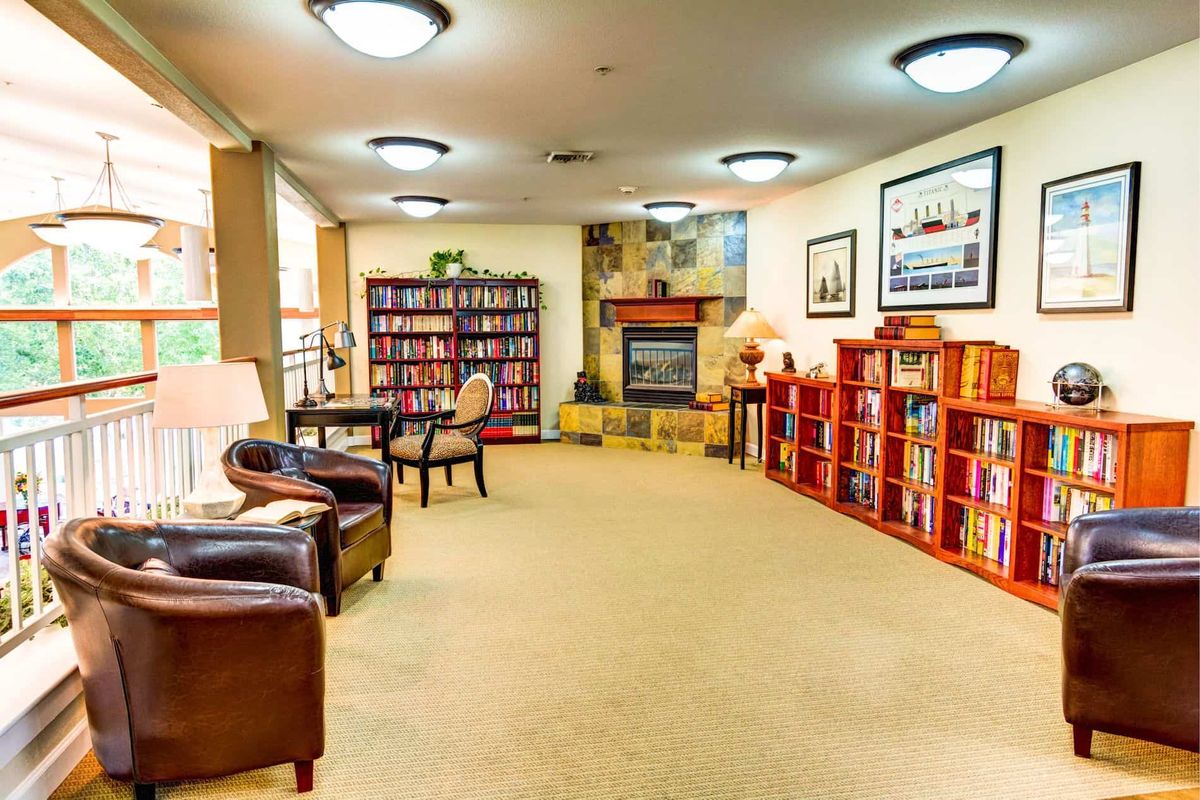 A cozy library with bookshelves, comfortable seating, and a fireplace.