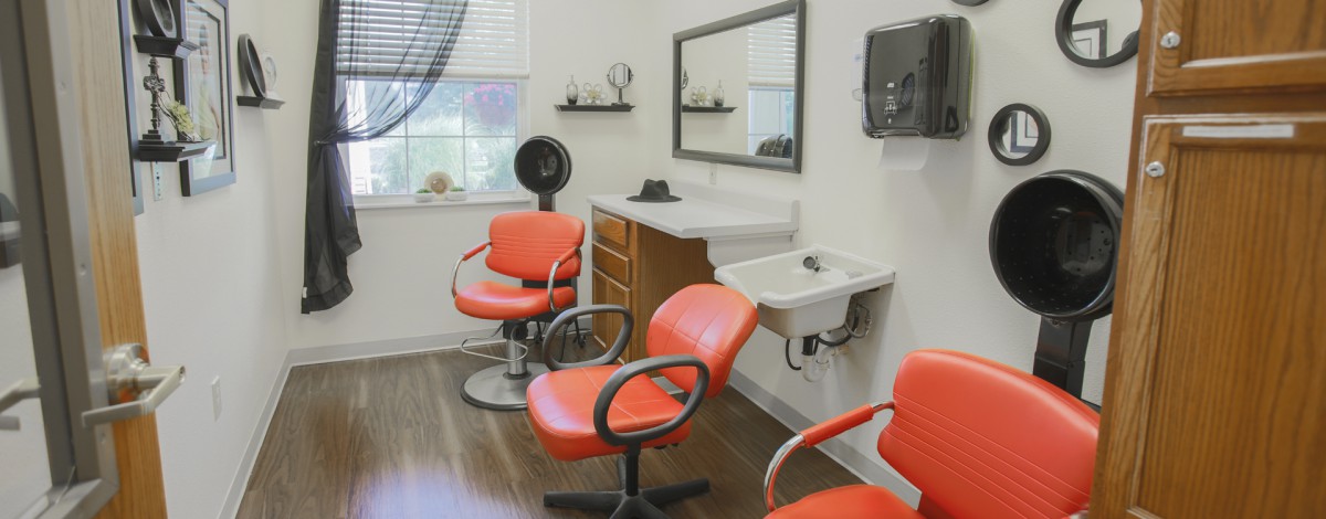A modern hair salon with orange chairs and a large mirror.