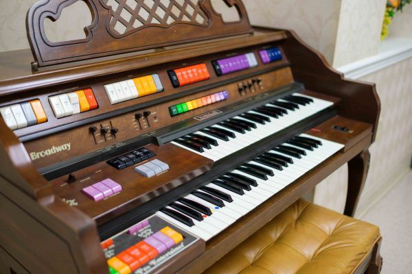 A vintage electric organ with multiple keys and colorful buttons.
