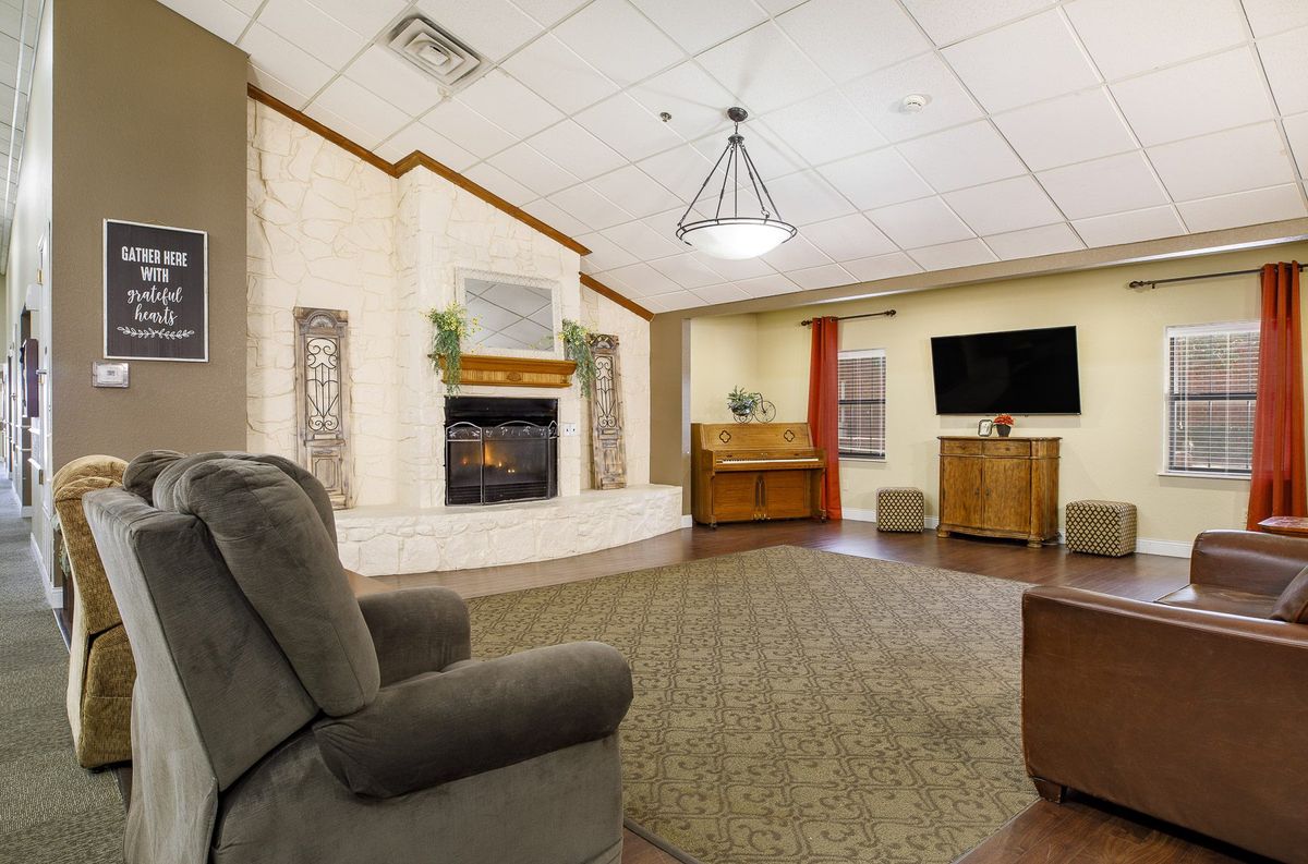 A cozy living room with a fireplace, piano, television, and comfortable seating.