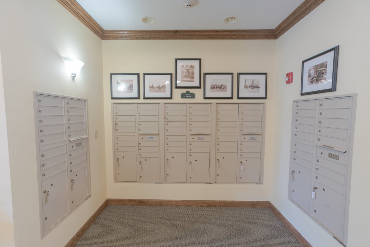 A hallway with mailboxes and framed artwork on the wall.