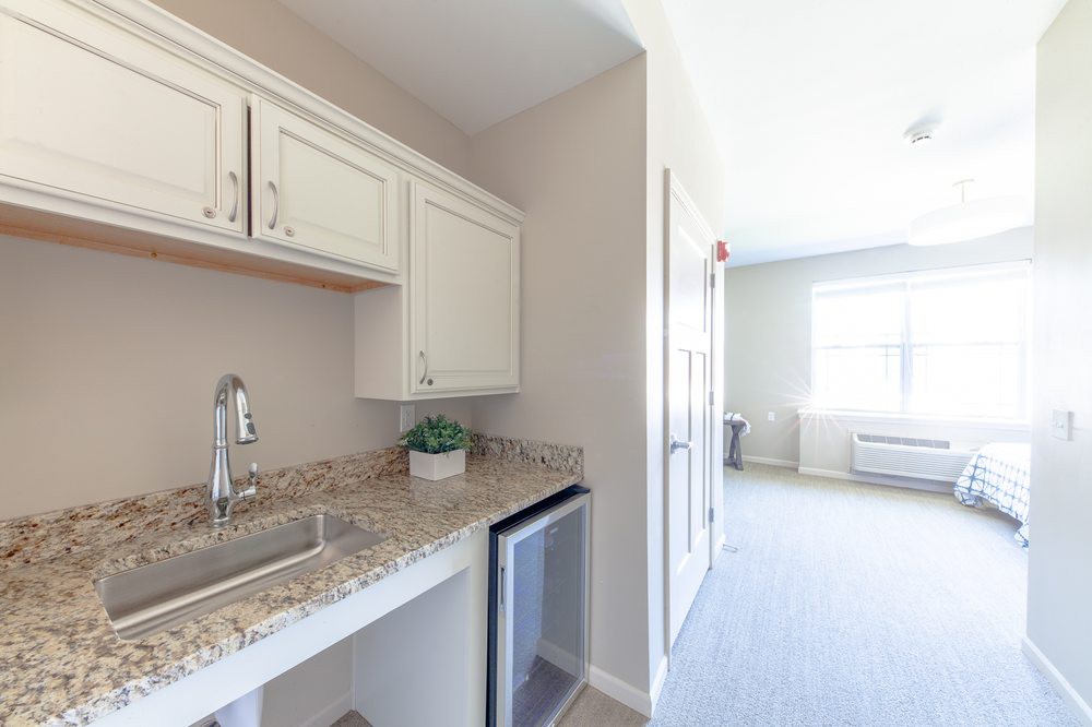 A small kitchenette with white cabinets, a granite countertop, and a sink.