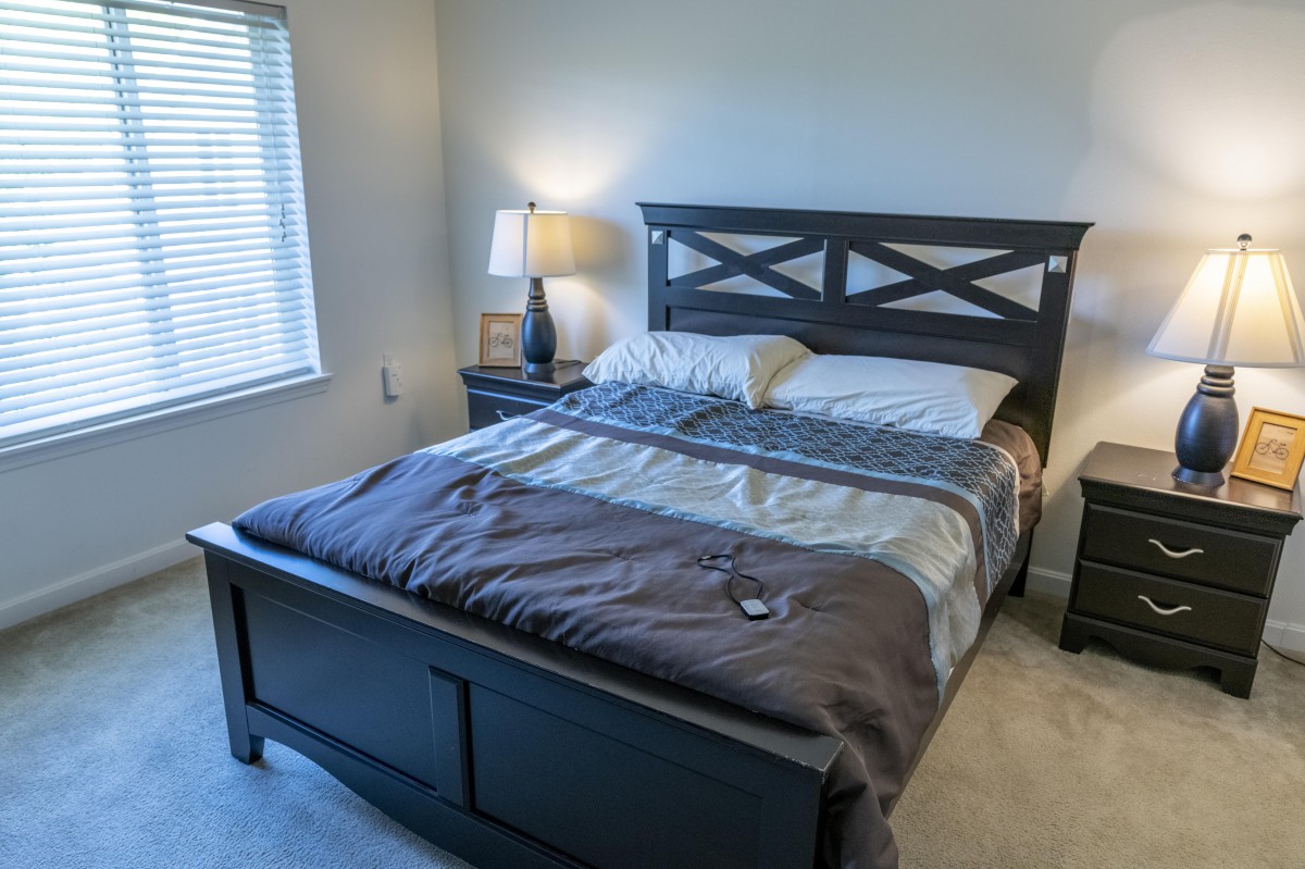 A neatly made bed in a cozy bedroom with a lamp and nightstand.