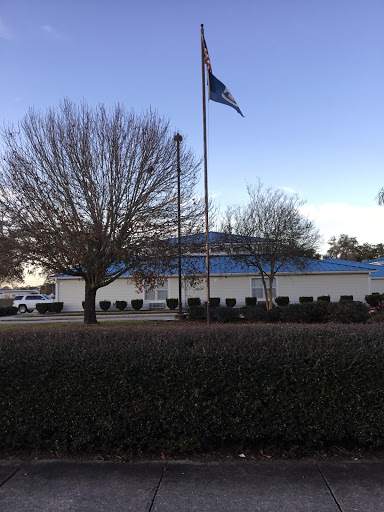 A view of a building with a flagpole in front, surrounded by trees.