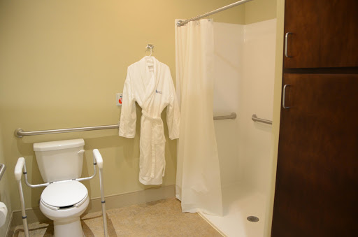 A cozy bathroom featuring a white robe hanging, a shower enclosure, and a toilet.