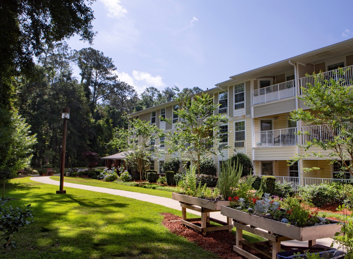 A scenic view of an apartment complex surrounded by lush greenery and a well-maintained lawn.