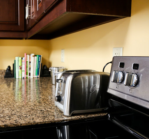 A cozy kitchen corner featuring a toaster, stove, and a stack of cookbooks on the granite countertop.